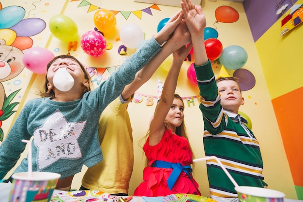 Free photo kids holding hands together on birthday party