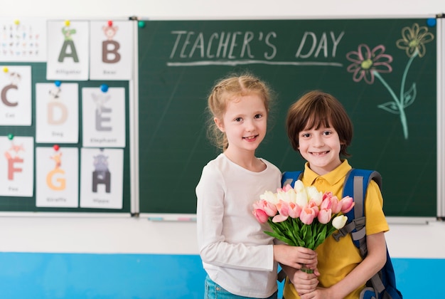 Kids holding together a bouquet of flowers for their teacher