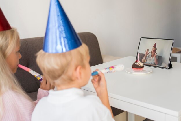 Kids at home in quarantine celebrating birthday over tablet