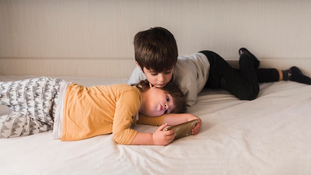 無料写真 スマートフォンでベッドにいる子供たち