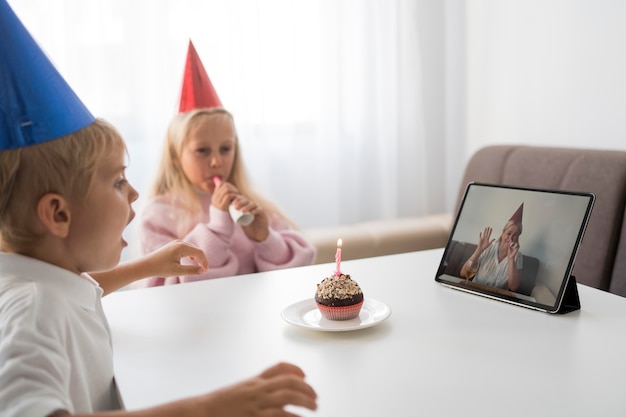 Бесплатное фото Дети в карантине дома празднуют день рождения за планшетом