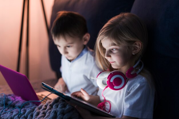 タブレットとノートパソコンを見ている子供たち