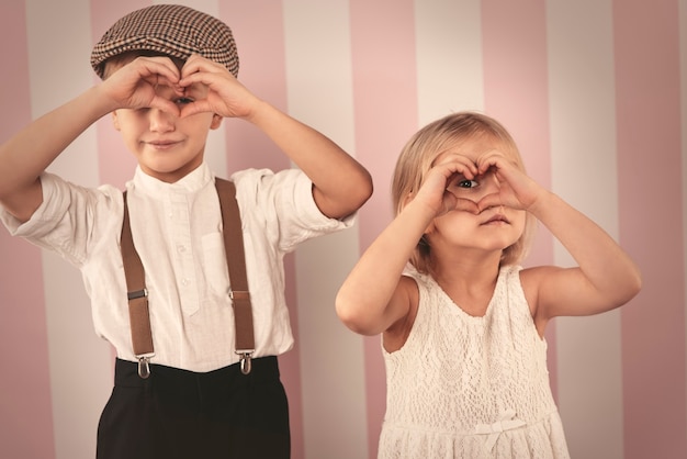 Foto gratuita bambini che guardano attraverso la forma del cuore dalle mani