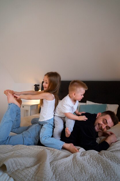 Kids making their father laugh by tickling him