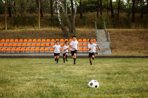 Free photo kids playing football supervised by football trainer