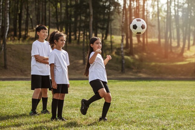 Kids playing football supervised by football trainer