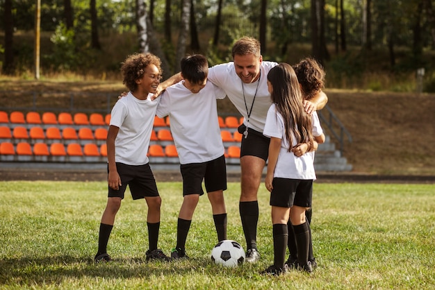 Kids playing football supervised by football trainer