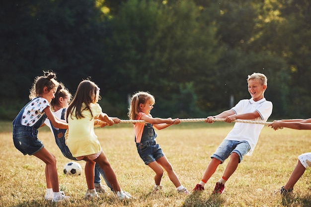 Premium Photo | Kids playing tug of war game in the beautiful meadow at sunny day.