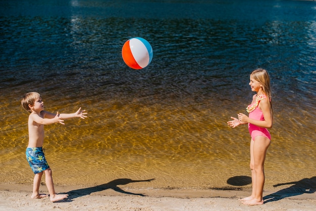 Free photo kids playing with beach ball standing near sea