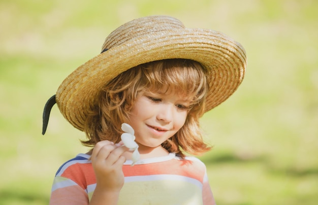 子供​の​肖像画​、​プルメリア​の​花​と​麦わら帽子​で​かわいい​子供​の​頭​を​閉じます​。