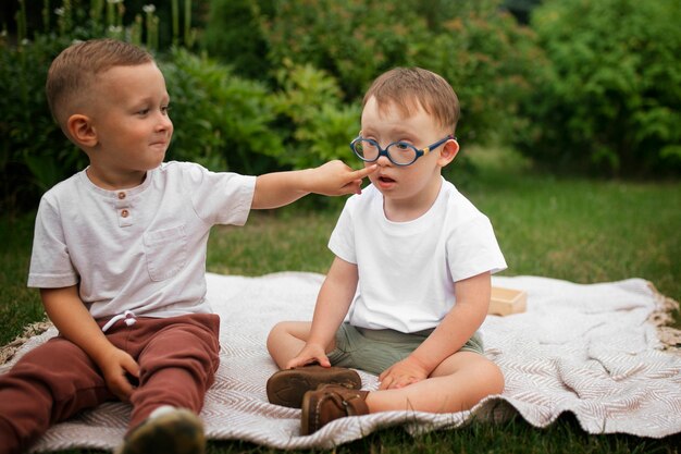 Kids sitting outdoors front view