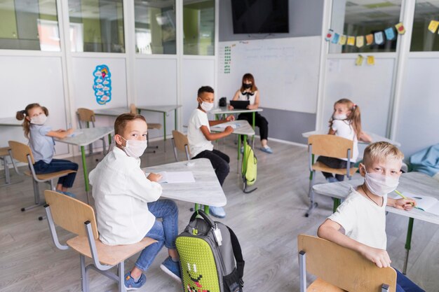 Kids and teacher wearing medical masks during pandemic