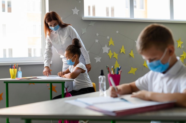 Kids and teacher wearing medical masks