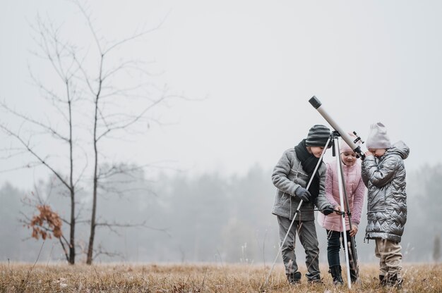 Kids using a telescope outside with copy space