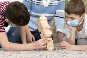 Foto gratuita bambini con maschere mediche che giocano a jenga con la madre