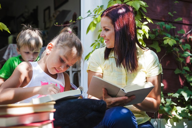 Дети с матерью пользуются книгами на крыльце