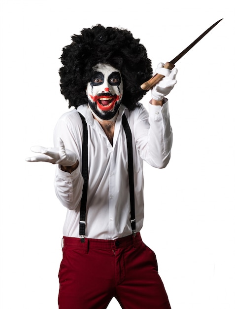 Free photo killer clown with knife making surprise gesture