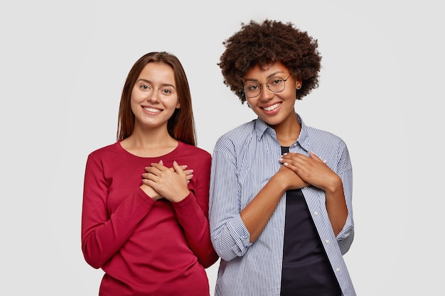 Free photo kind couple keep both hands on chest, express gratitude