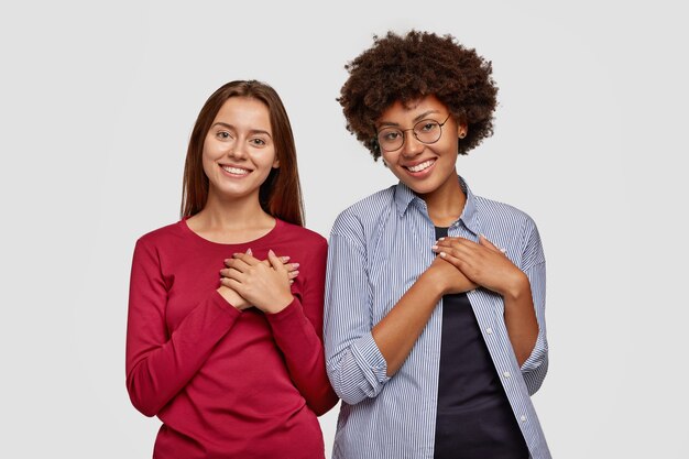 Kind couple keep both hands on chest, express gratitude