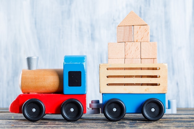 Kindergarten concept with wooden blocks, kid toys on wooden and grungy background side view.