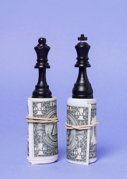 Free photo king and queen pieces of chess standing on equal amount of money