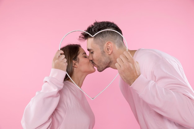 Free photo kiss of man and woman holding symbol of heart
