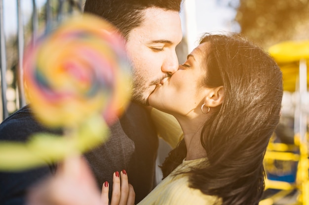 Kissing couple holding a lollipop