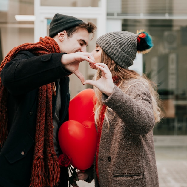 Kissing couple showing heart gesture