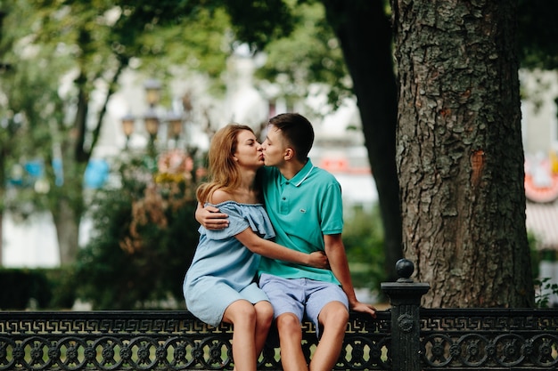 Kissing couple sitting on fence outside