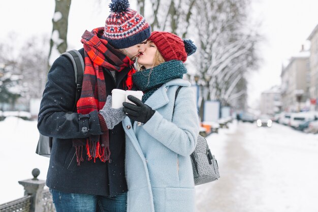 スタイリッシュなカップルを雪の通りにキス