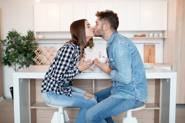 부엌에서 젊은 행복 한 남자와 여자, 아침에 키스, 아침에 부부 함께 웃 고, 차를 마시고, 키스, 사랑