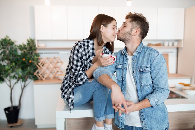 キッチンで幸せな若い男と女にキス、朝食、朝一緒にカップル、笑顔、お茶