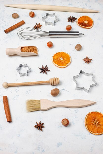 Kitchen baking utensils with spices for cookies and cookie cutters on light surface