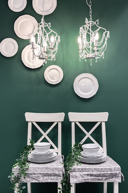 무료 사진 짙은 녹색 배경에 흰색 의자에 접시 세트가 있는 주방 구성.