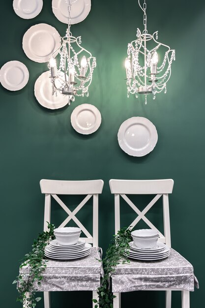 Kitchen composition with a set of dishes on white chairs on a dark green background.