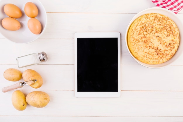 Foto gratuita desktop da cucina con torta e tablet