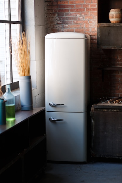 Free photo kitchen interior in dark textured colors with white modern retro fridge, rustic brick wall