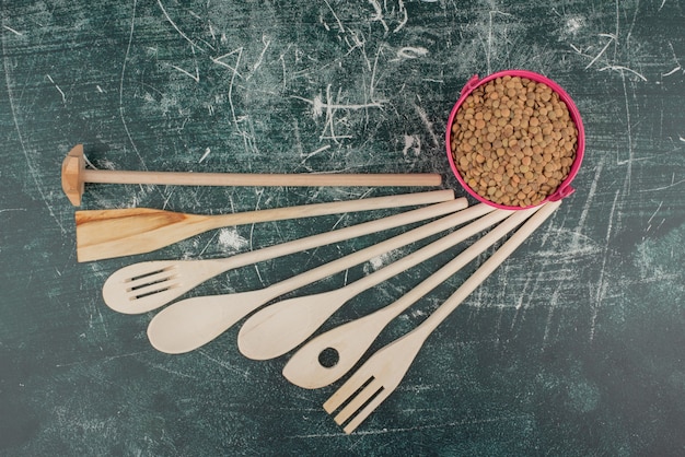 Кухонные инструменты с розовым ведром орехов на мраморном фоне. Фото высокого качества