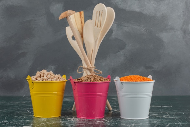 Kitchen tools with three colorful buckets of nuts on marble wall.