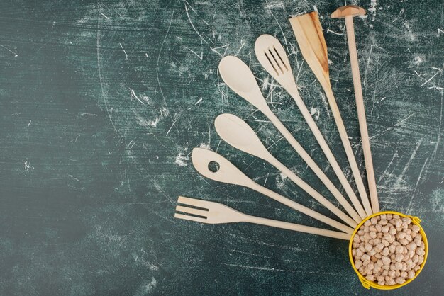 Кухонные инструменты с желтым ведром орехов на мраморной предпосылке. Фото высокого качества