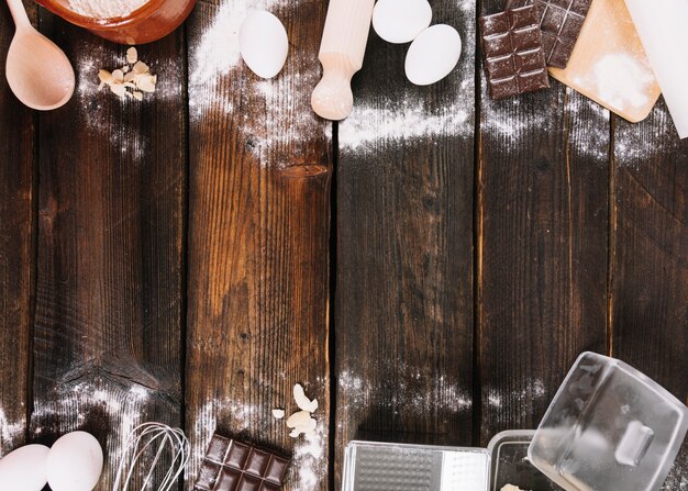 Kitchen utensil and ingredients for baking cake on wooden plank backdrop