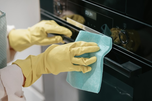 Foto gratuita lavoro in cucina. giovane donna dai capelli scuri che pulisce gli elettrodomestici da cucina