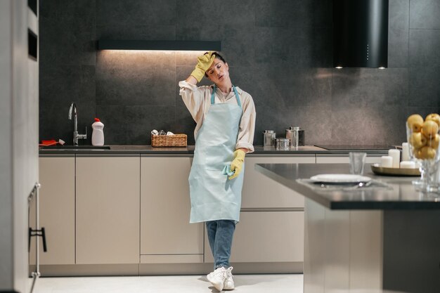На кухне. Молодая женщина в фартуке и перчатках на кухне