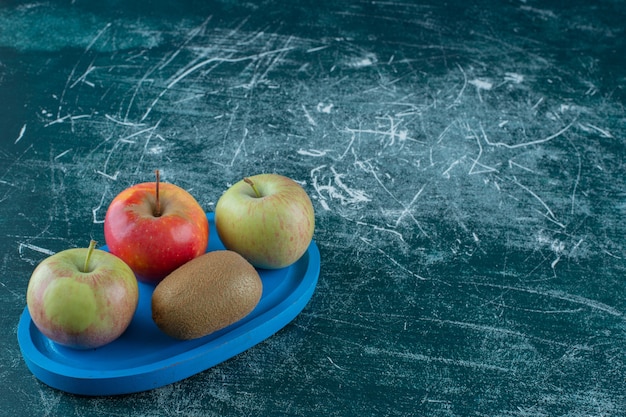 大理石のテーブルの上に、木の板の上にキウイとリンゴ。