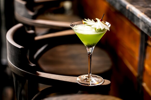 Kiwi fruit cocktail in martini glass garnished with apple slices on bamboo skewer