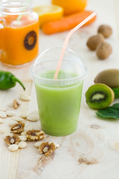 Kiwi juice, nuts and fresh fruits on wooden background.