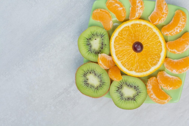 Fette di kiwi, arancia e mandarino sulla zolla verde. foto di alta qualità