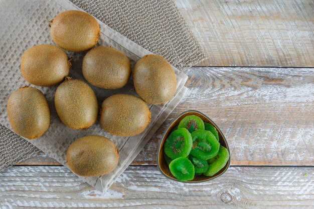 Kiwi with dried slices, kitchen towel flat lay on wooden table