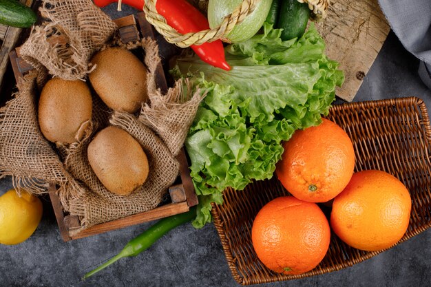 Kiwies and oranges in rustic wooden trays.