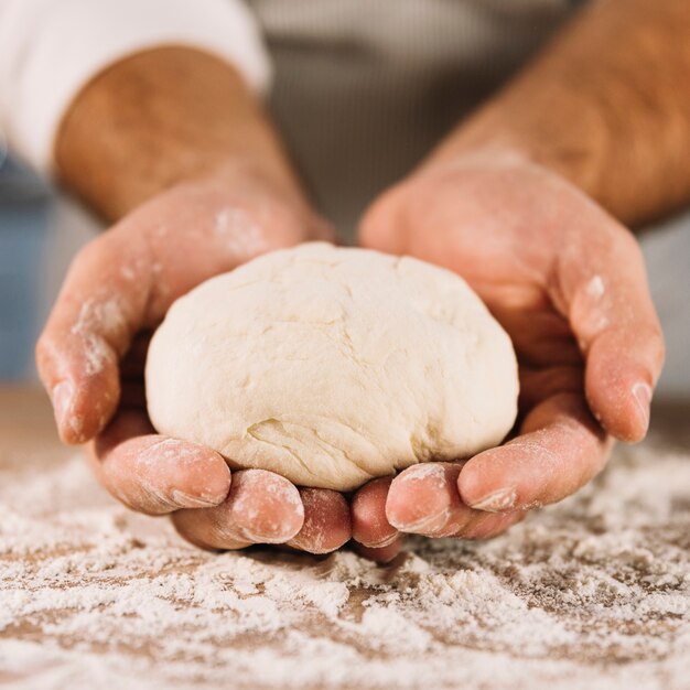 Knead dough in hand on wooden table with flour